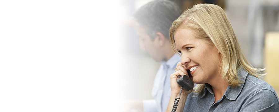 A smiling business woman takes a phone call using Shentel’s business phone and internet services. Shentel offers one of the best multi line phone systems for small business.